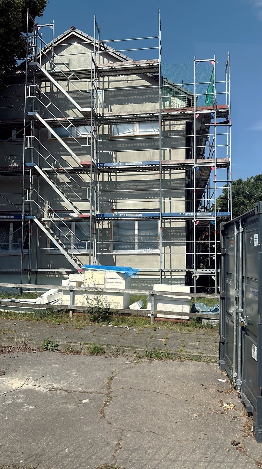 Eingerüstetes Wohnhaus mit frisch aufgezogenem Putz bei Sonnenschein